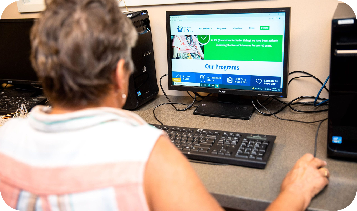 An elderly woman typing on a public computer